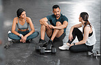 Fit, active and healthy gym team talking, bonding and planning workout, training and exercise in wellness center. Sporty, athletic or strong man and women on break from intense dumbbell weightlifting