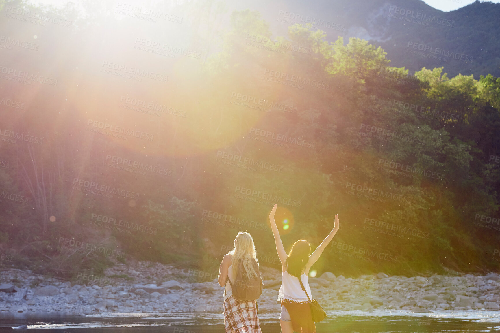 Buy stock photo Women, back or sunshine with freedom by lake for holiday, hiking trip or break in nature. Young, female person or friends with sunlight by water, river or pond for tourism, travel or carefree journey