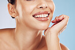 Closeup face beautiful young mixed race woman. Attractive female smiling in studio isolated against a blue background. Practising good oral and dental hygiene for healthy mouth, teeth and gums