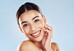 Closeup face beautiful young mixed race woman. Attractive female touching her face in studio isolated against a blue background. A skincare regime to keep your skin soft, smooth, glowing and healthy