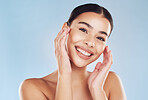 Closeup face beautiful young mixed race woman. Attractive female touching her face in studio isolated against a blue background. A skincare regime to keep your skin soft, smooth, glowing and healthy