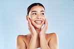 Closeup face beautiful young mixed race woman. Attractive female touching her face in studio isolated against a blue background. A skincare regime to keep your skin soft, smooth, glowing and healthy