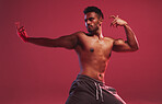 Athletic hispanic man standing in fighting position. Masculine man showing kick fighting technique while standing against a red background 