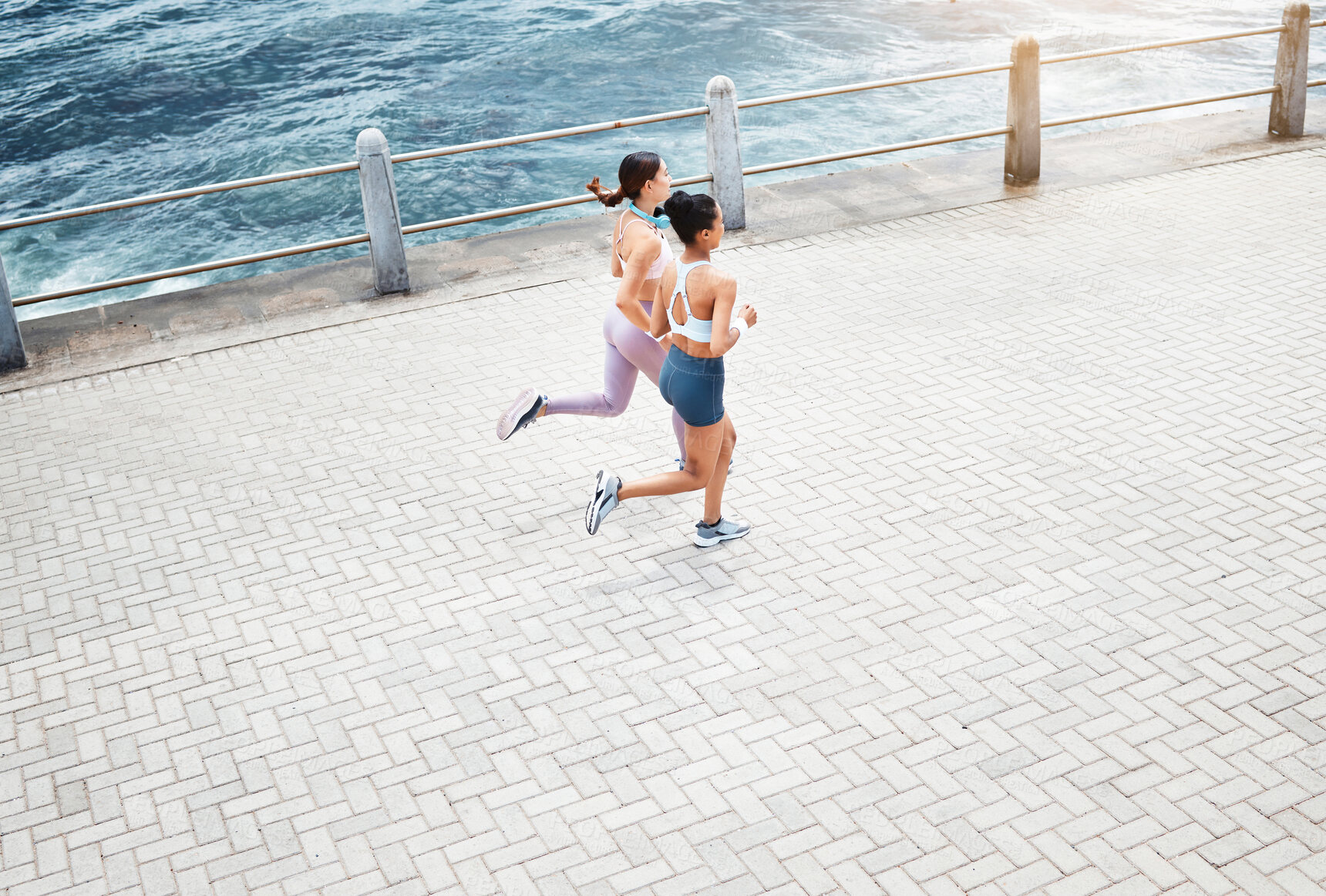 Buy stock photo Beach, women and fitness friends running on sidewalk at the ocean for exercise, cardio workout and training outdoors. Healthy, wellness and sports runners exercising together at sea or waterfront