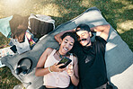 Phone, love and picnic with a couple lying on a field of grass outdoor while enjoying the freedom of nature together. Mobile, relax and summer with a male and female in park for bonding or dating