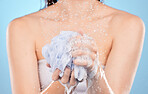 Woman, shower and hands with sponge close up or body cleaning or washing for skincare hygiene in studio. Model, skincare cleaming and foam sponge for cosmetics scrub or  body care in blue background