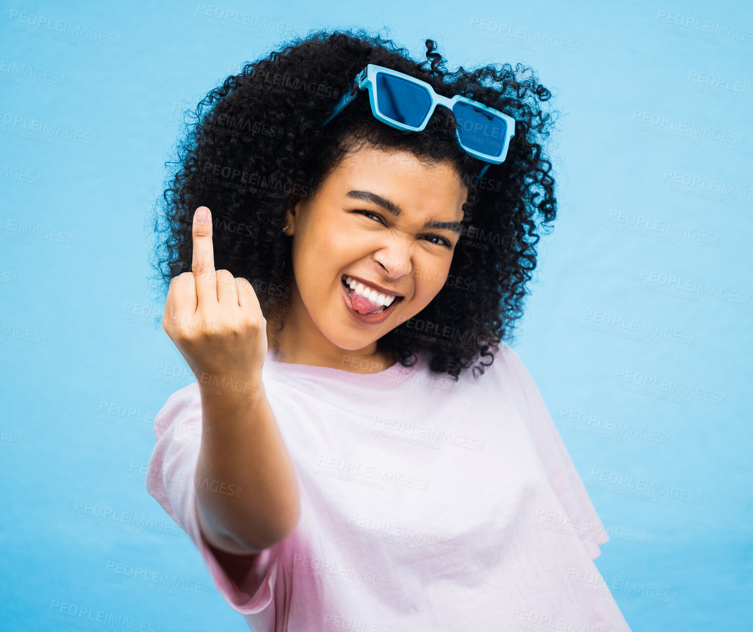 Buy stock photo Portrait, middle finger and hand, emoji and black woman in studio, rude and carefree on a blue background. Face, rebel and hands by girl for message, attitude and expression, personality and isolated