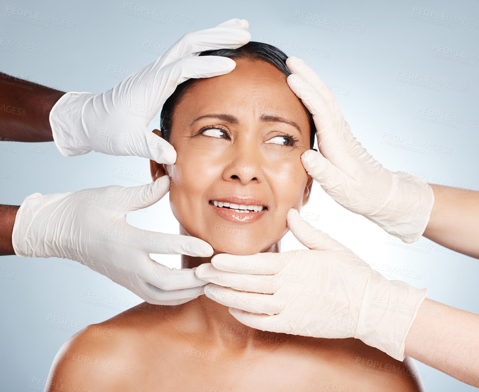 Buy stock photo Plastic surgery, scared and face of woman with hands from doctors isolated on blue background. Skincare, check and mature person worried about facelift, cosmetic and facial surgeon professionals