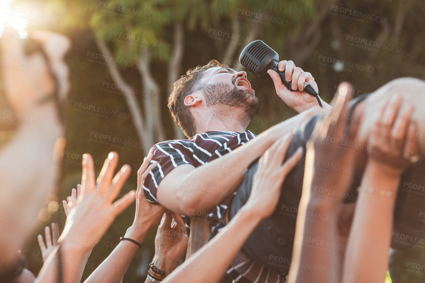 Buy stock photo Crowd, surfing and man singing at party, outdoor music festival or social gathering. Microphone, energy and male singer diving in audience group at performance event, celebration or crazy fun weekend