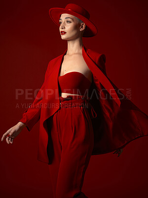 Buy stock photo Runway, fashion and a model woman on a red studio background for elegant art or trendy style. Aesthetic, beauty and wind with a young female person looking edgy, classy or unique in a clothes suit