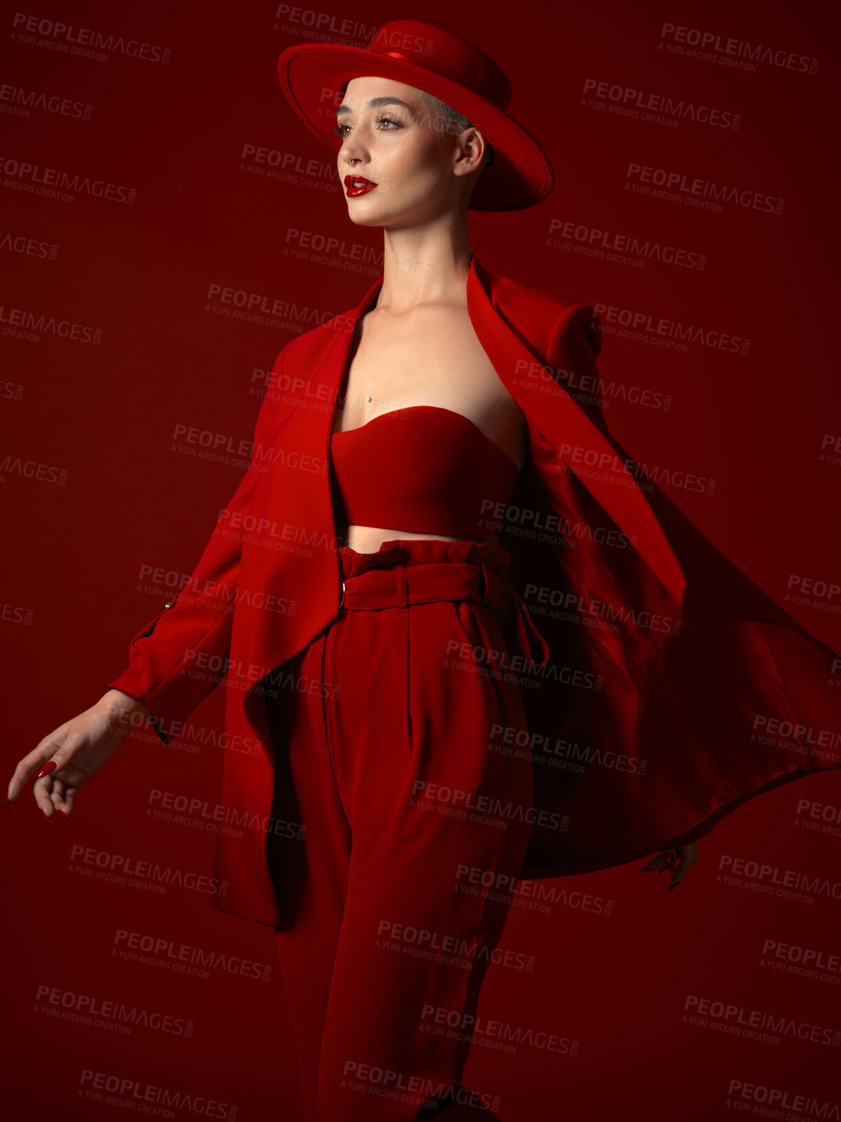 Buy stock photo Runway, fashion and a model woman on a red studio background for elegant art or trendy style. Aesthetic, beauty and wind with a young female person looking edgy, classy or unique in a clothes suit