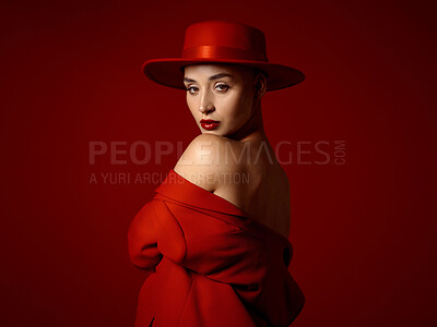 Buy stock photo Portrait, fashion and shoulder with a woman on a red studio background for elegant or trendy style. Aesthetic beauty, art and hat with a young female model looking edgy or classy in a unique outfit