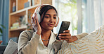 Headphones, indian woman and cellphone for music in home, listen and song in living room. Joyful, lounge and online audio streaming for sing along app, karaoke and games for female person on sofa 