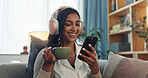 Headphones, indian woman and cellphone for social media in home, laugh and music in living room. Coffee, relax and online audio streaming or podcast for break, chai tea or happy female person on sofa