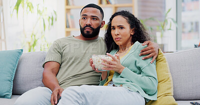 Buy stock photo Couple, scared and watching tv on sofa with popcorn in home for horror film, streaming and hug in living room. Man, woman and subscription with snack, fear and eating on couch for movie date in house