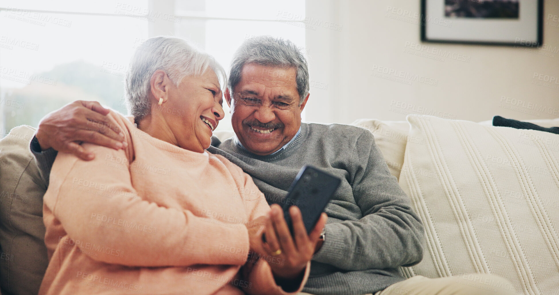 Buy stock photo Senior couple, phone and happy on sofa with hug, reading and notification with funny story in home. Woman, man and smartphone in retirement, relax and embrace with comic memory on mobile app in house