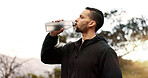 Man, drinking water or profile in nature for fitness, hydration or electrolytes for energy. Athlete, break or liquid in bottle for refreshment, healthy body or rest from running on mountain in Brazil