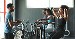 People, fitness trainer and tired on stationary bike at gym for exercise, training and workout with sweat. Cycling machine, energy and building muscles with cardio for health, self care and wellbeing