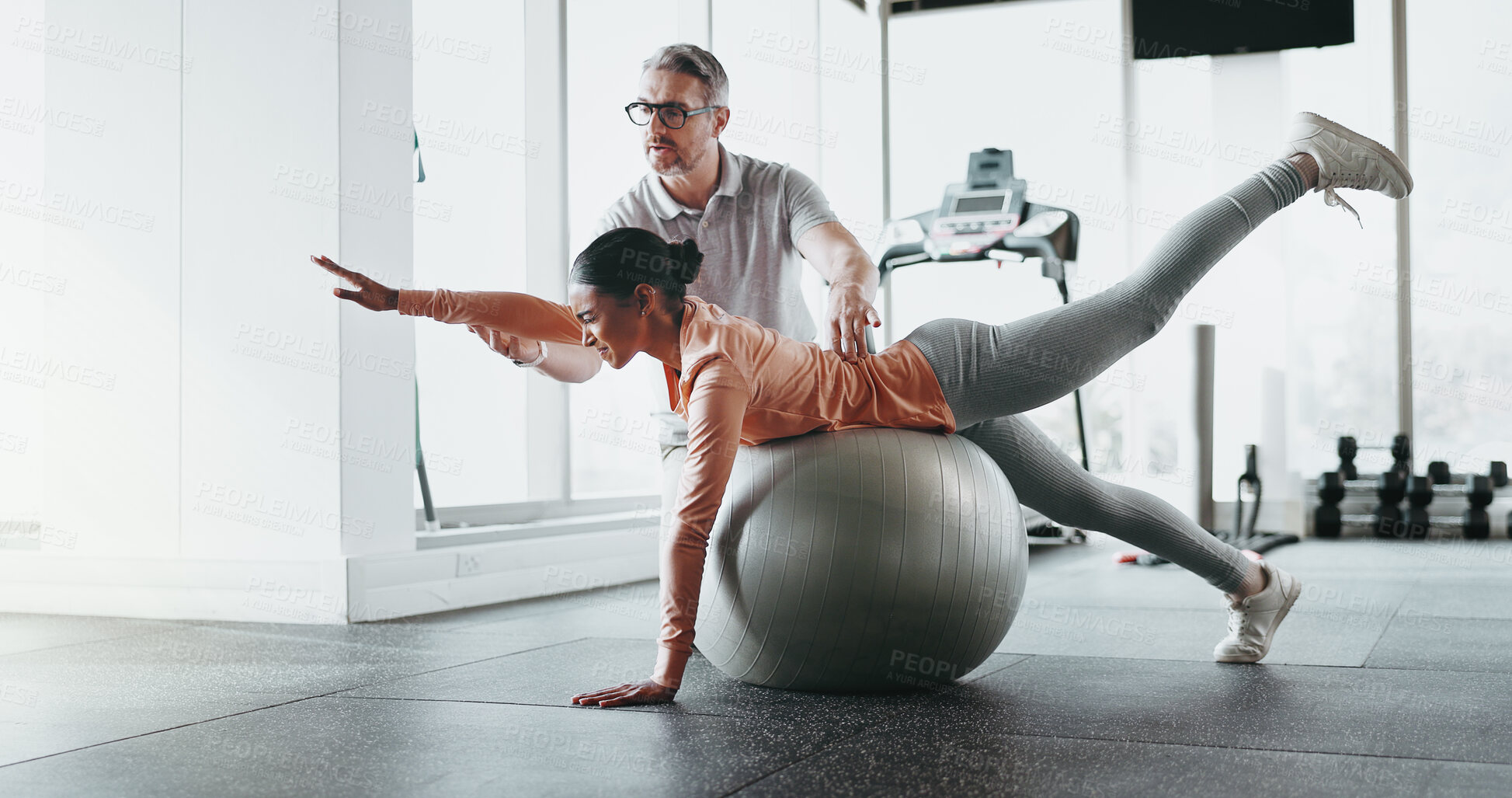 Buy stock photo Ball, woman and personal trainer in gym for stretching, rehabilitation and balance training. Man, client and physiotherapy in fitness center for core strength, practice and help in exercise activity