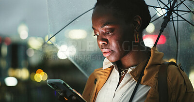 Buy stock photo Black woman, outdoor and umbrella with smartphone at night on mobile app for ehailing for taxi ride. Female person, employee and texting online on website for requesting transportation in city