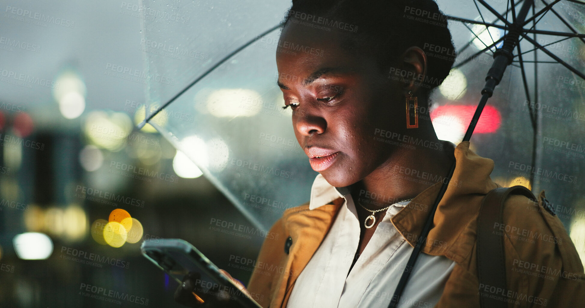 Buy stock photo Black woman, outdoor and umbrella with smartphone at night on mobile app for ehailing for taxi ride. Female person, employee and texting online on website for requesting transportation in city