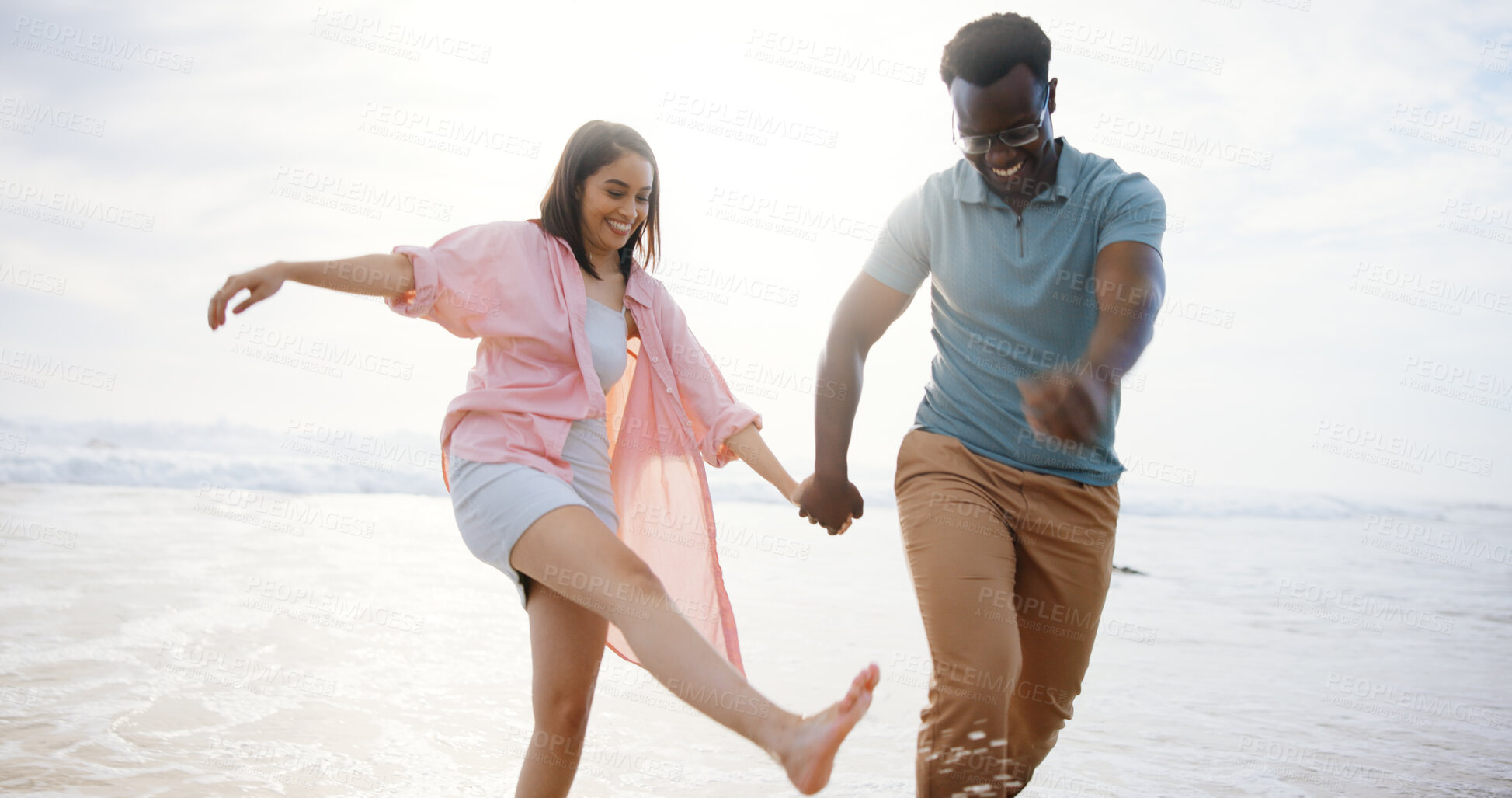 Buy stock photo Laugh, holding hands and splash with interracial couple at beach for travel destination, summer or honeymoon vacation. Relax, tropical and adventure with man and woman for holiday, bonding or romance