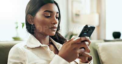 Buy stock photo App, phone and serious Indian woman on sofa in living room of home for communication or research. Internet, social media and text message with person typing on mobile in apartment for networking