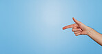 Finger, point and hand of person in studio for information, promotion and announcement of news. Arm, gesture and direction by mockup space for answer, review or feedback of opinion on blue background