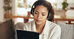 Headphones, remote work and tablet with business woman on sofa in home living room for video call. Learning, listening and webinar with African employee in apartment for education or virtual meeting