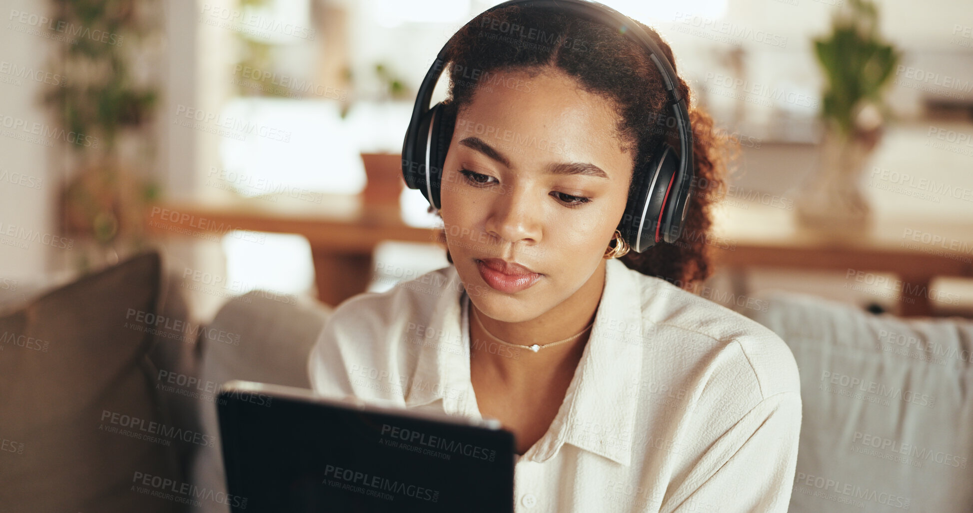 Buy stock photo Headphones, remote work and tablet with business woman on sofa in home living room for video call. Learning, listening and webinar with African employee in apartment for education or virtual meeting