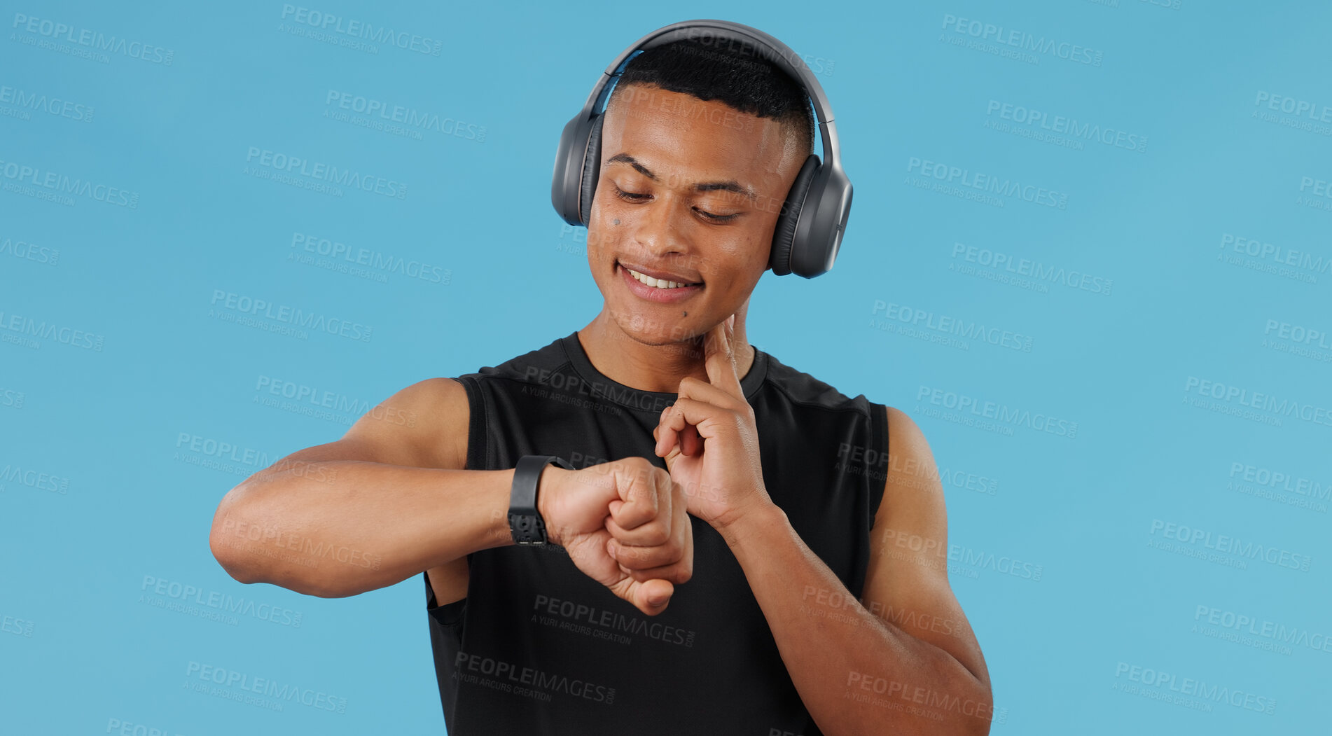 Buy stock photo Man, fitness watch and check pulse in studio, headphones and music for exercise on blue background. Male person, monitor heart rate and tracking progress on app, athlete and gear for cardio stats