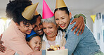 Family, hug and celebration with grandmother on birthday for surprise, present and special event at home. Party hat, happy people and senior woman with gesture of love for cake, candles and dessert