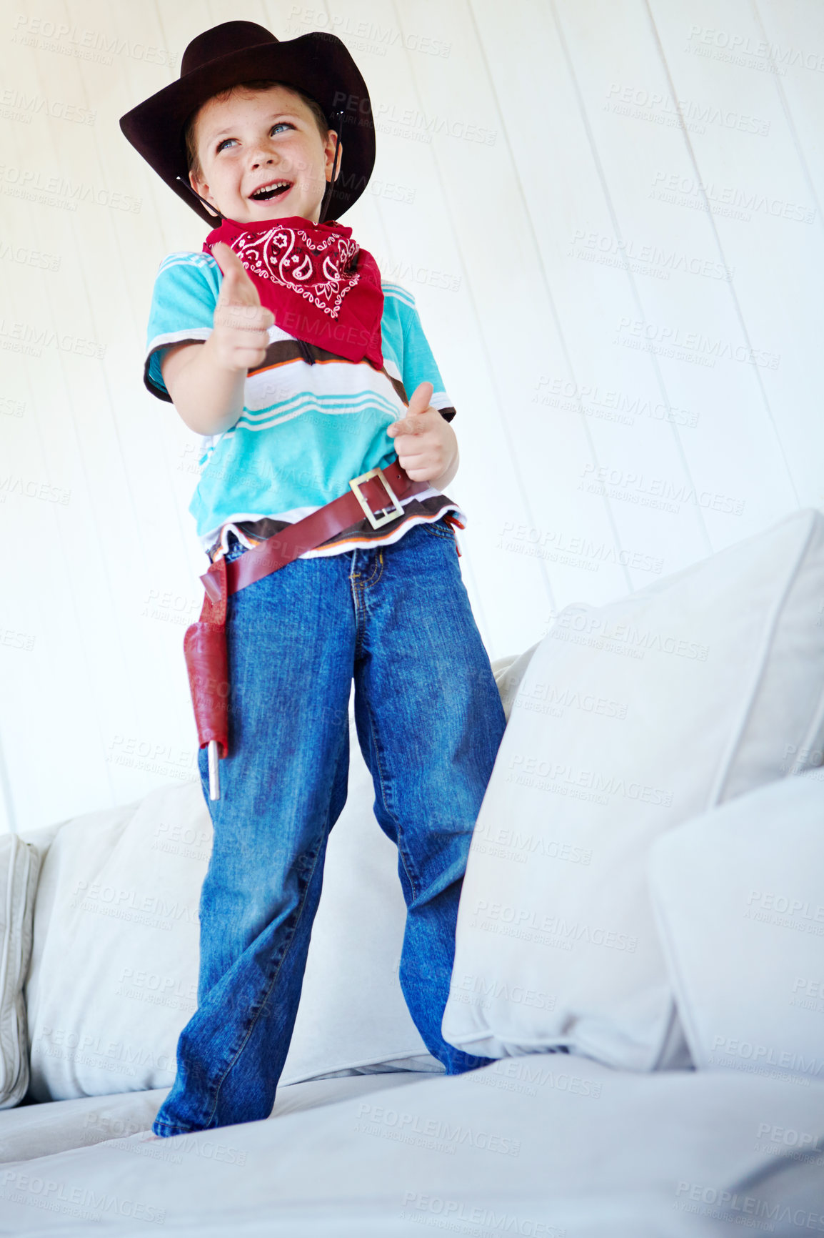 Buy stock photo Happy kid, cowboy and play game with gun gesture for fantasy and creative cosplay in home lounge. Boy child, western costume and pistol fingers on sofa for shooting, excited or dress up for halloween