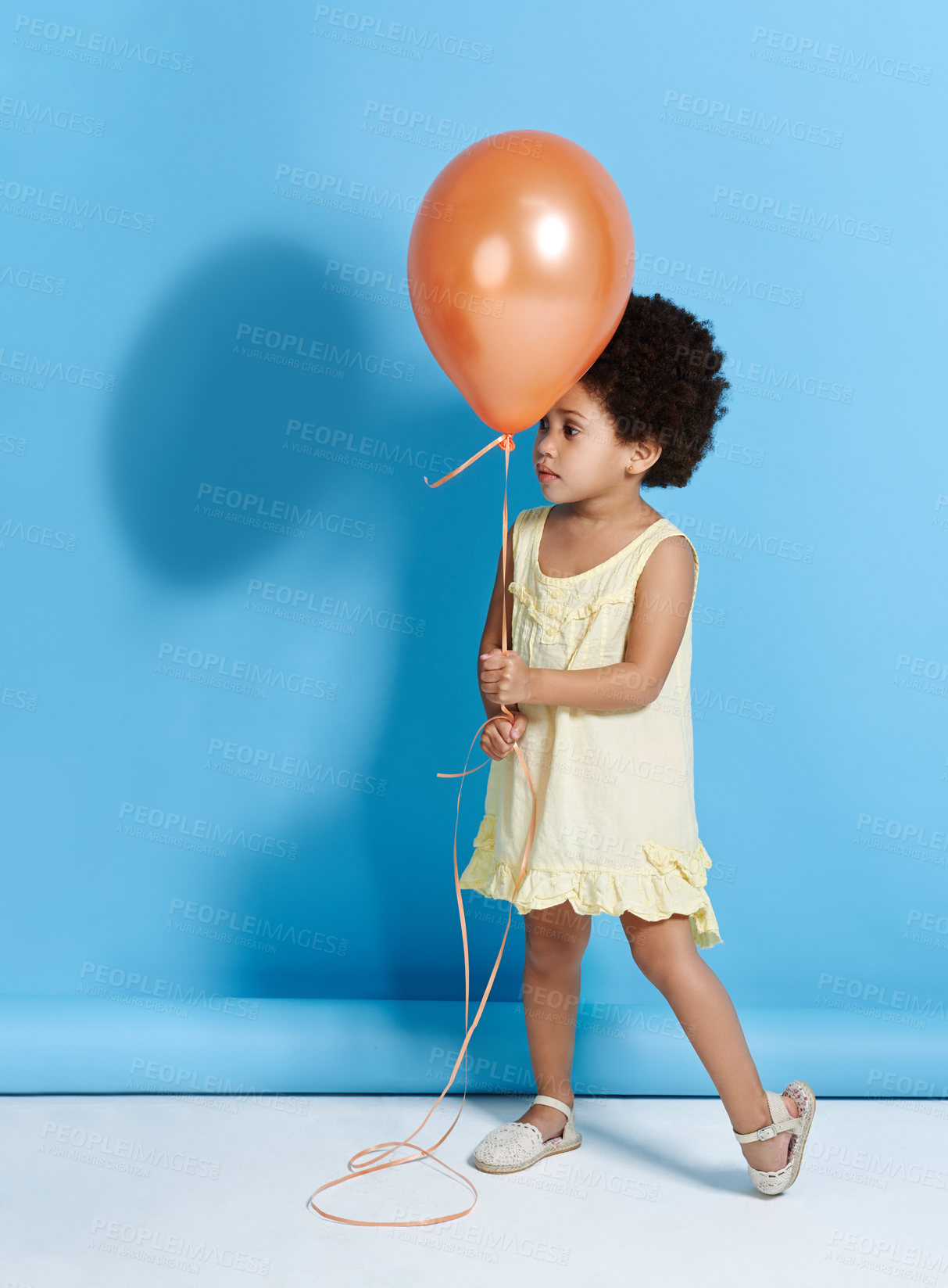 Buy stock photo Cute, girl and balloon for fun, happiness and childhood on blue studio background. Mockup space, model and African kid with decoration for party, event and energy with break, playful and birthday