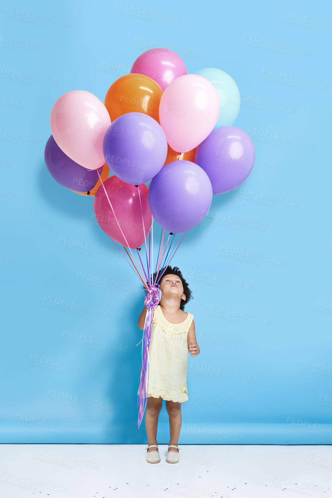 Buy stock photo Balloon, happy and child in studio for birthday, party and celebration with decoration. Playful, childhood and isolated young girl looking up for special day, surprise and present on blue background