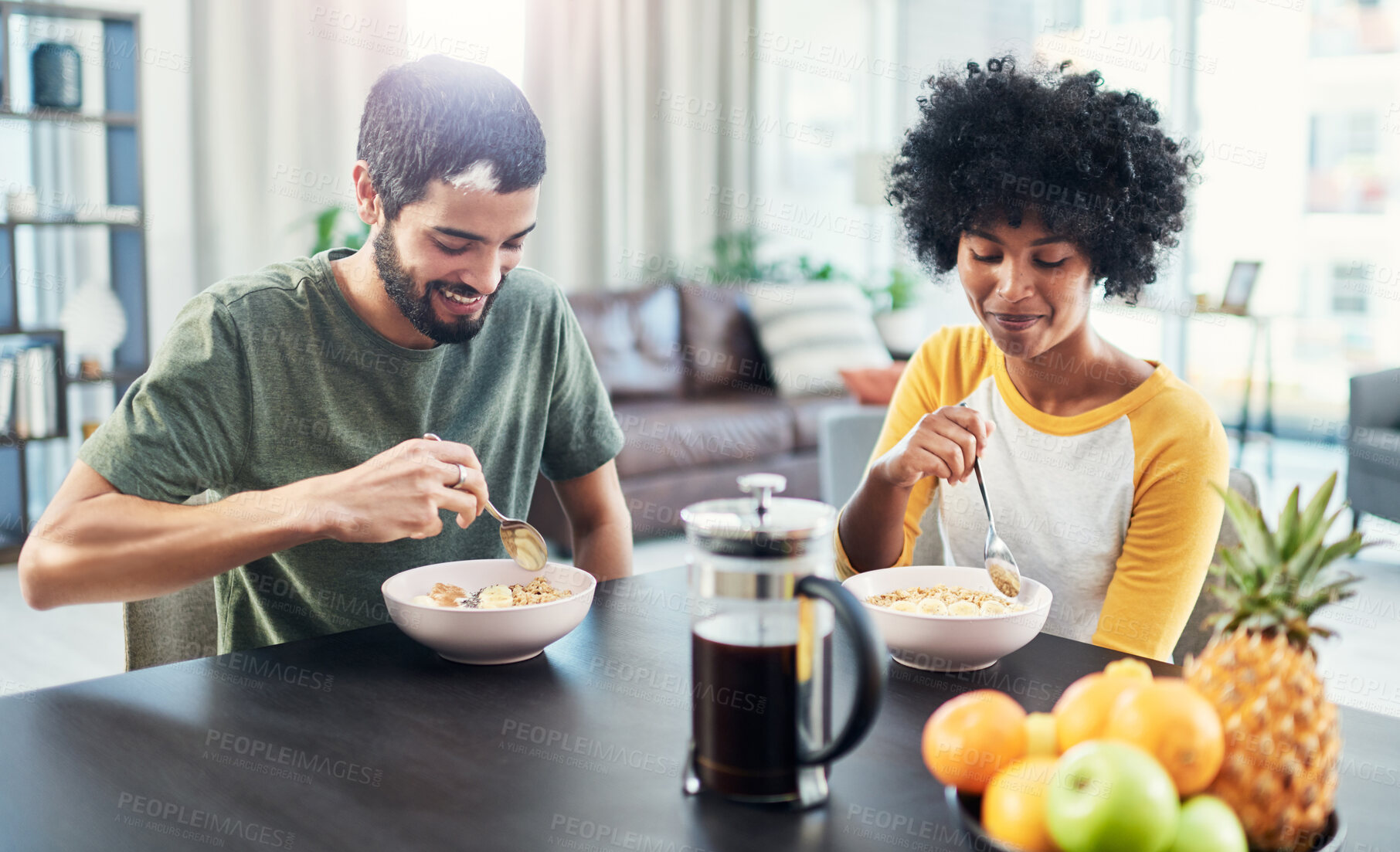 Buy stock photo Couple, happy and eating breakfast in home for morning routine, nutrition and cereal for protein. Interracial people, smile and porridge at dining table for wellness diet, start day and healthy food