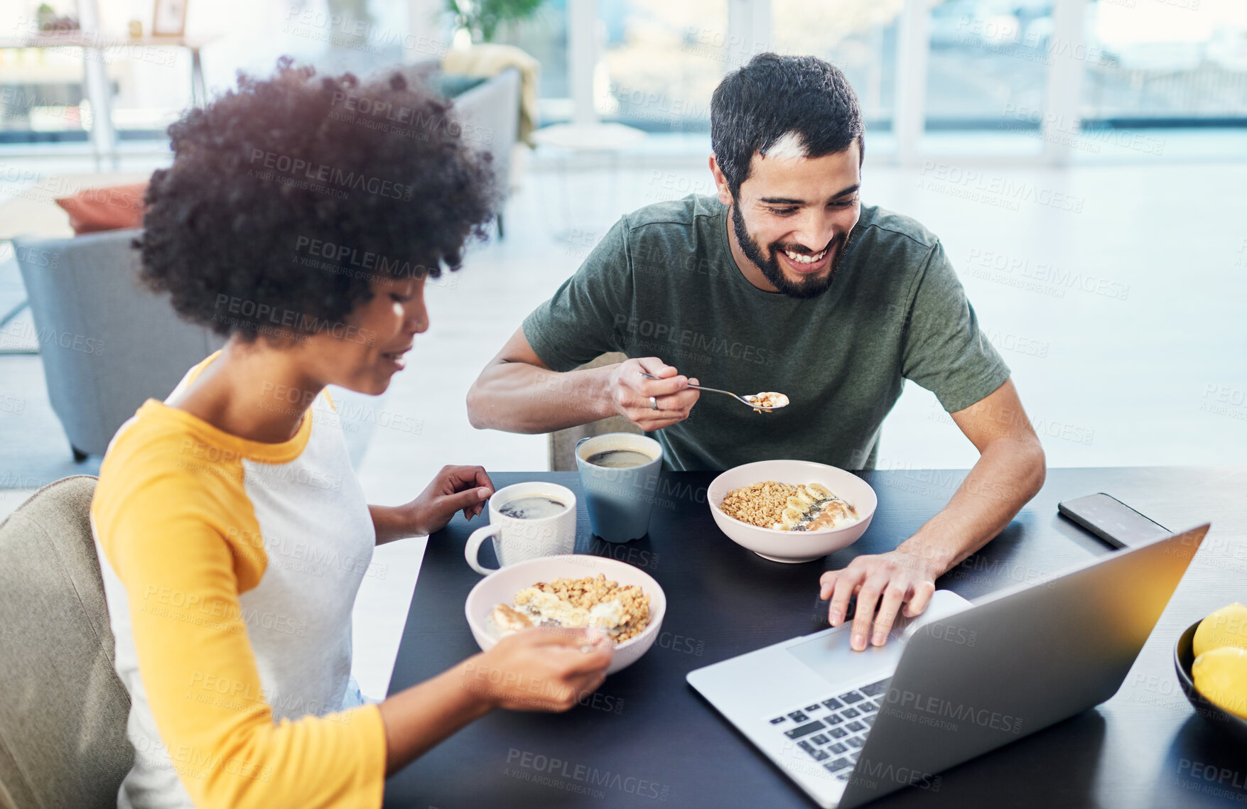 Buy stock photo Couple, smile and eating breakfast in home for morning routine, nutrition and cereal with laptop. Interracial people, happy and porridge at dining table for wellness diet, start day and healthy food