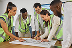 Closeup of a happy diverse multiracial group of architect colleagues analyzing a blueprint design on a building and discussing plans for the next project. Team of young and senior designers working on a strategy for a building construction plan while wear