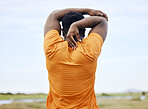 Rearview of a runner stretching on a field. An African American man focused on warming up. A sportsman staring forward away from the camera