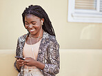 Happy african american woman with using earphones to listen to music on smartphone or watch funny video online. Stylish young woman using mobile app while walking on city street