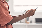 Businessman typing a message on a phone at work. One creative male businessperson using social media on his cellphone in an office. Business professional checking his emails on a smartphone