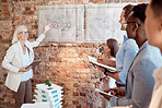 Group of diverse architects discussing plans, blueprints and schematics during a meeting in their office boardroom. Business people brainstorming and planning their upcoming project development