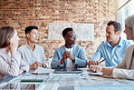 Group of diverse architects discussing plans, blueprints and schematics during a meeting in their office boardroom. Business people brainstorming and planning their upcoming project development