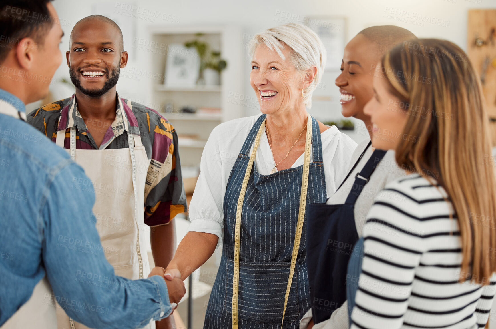 Buy stock photo Creative, handshake and discussion with client, group and agreement in workshop, fashion designer and apron. Tailor, holding hands and people in business meeting and collaboration in design studio