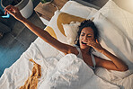 A young mixed race woman yawning and stretching while  lying in bed. An attractive Hispanic female waking up from a her sleep and getting ready to begin her day