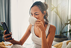 A beautiful young Hispanic woman enjoying a warm cup of coffee for breakfast. One mixed race female drinking tea while checking her social media