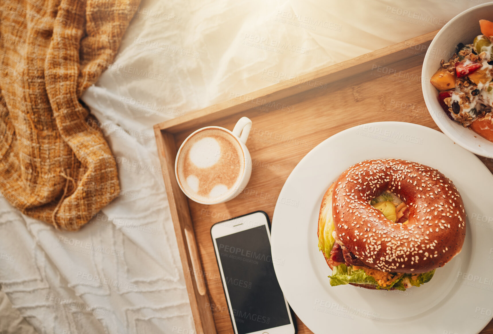 Buy stock photo Bagel, tray and food with coffee on bed above for room service, meal or breakfast at hotel. Top view, bread and snack with phone screen, cappuccino or muesli for catering or hospitality in bedroom