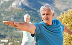 Seniors living a healthy lifestyle and exercising outdoors. Senior couple standing in warrior pose while practicing yoga in nature on a sunny day