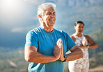 Senior man meditating with joined hands and closed eyes breathing deeply. Mature people doing yoga in nature living a healthy active lifestyle in retirement