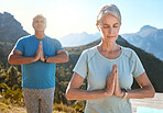 Senior couple meditating with joined hands and closed eyes breathing deeply. Mature couple doing yoga in nature living a healthy and active lifestyle in retirement